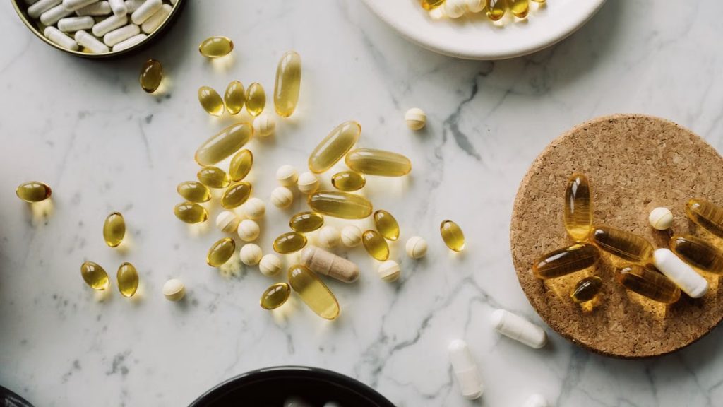 Health supplements and vitamins in gelatin capsules arranged in various container on marble surface